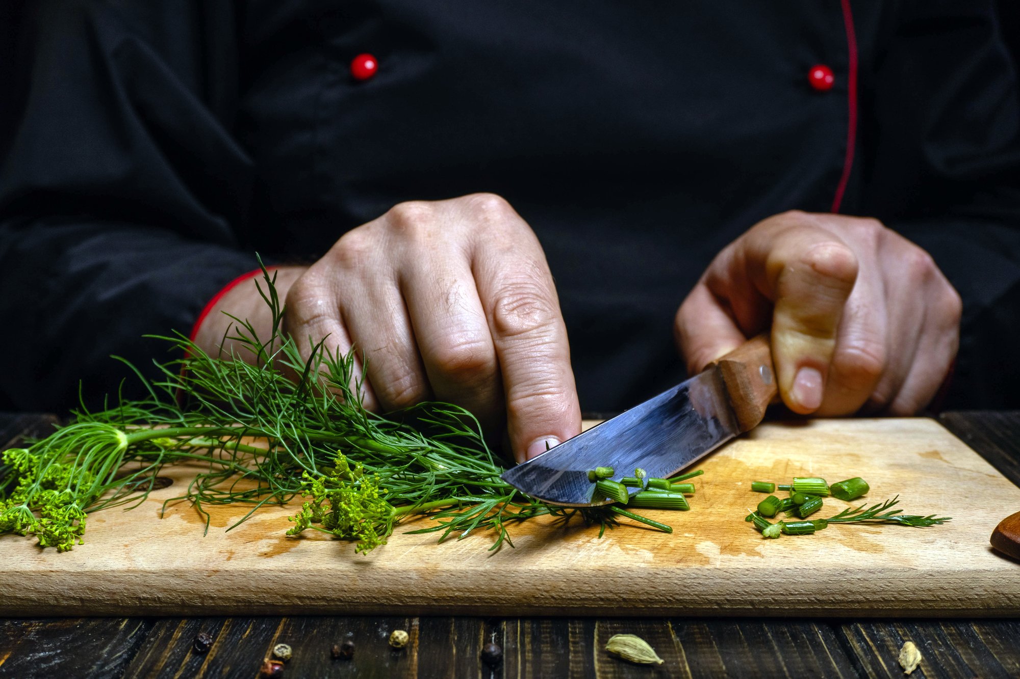 Close-up of chef's hands slicing herbs